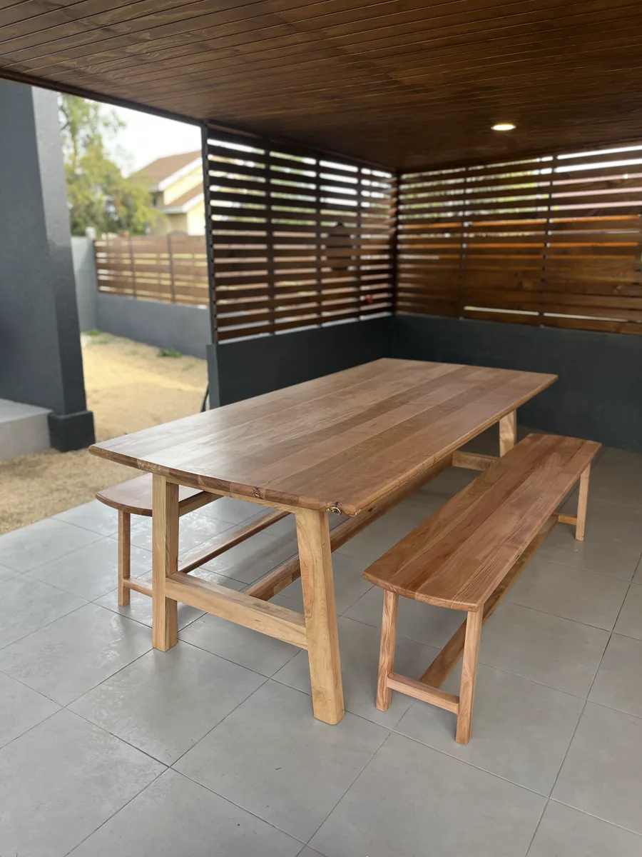 Mesa de madera con dos bancas bajo una terraza techada